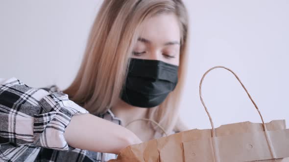 Woman in a Black Protective Mask Is Unpacking a Craft Paper Bag