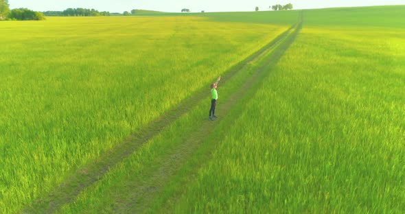 Sporty Child Standing in Green Wheat Field with Raised Hands Up. Evening Sport Training Exercises