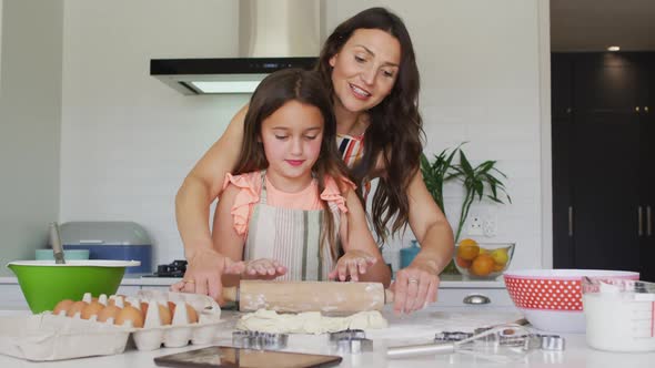 Happy caucasian mother and daughter baking together in kitchen