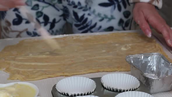 A Woman Butters A Rolled Out Dough. Prepares Cruffin With Raisins And Candied Fruit