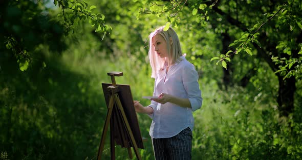 Woman Draws on an Easel on the Nature