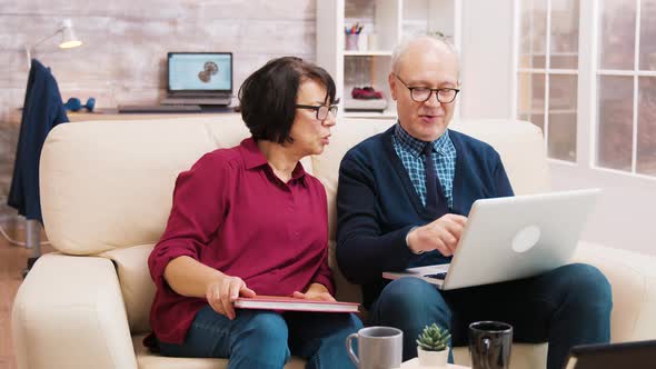 Elderly Age Couple Using Laptop While Sitting on Sofa