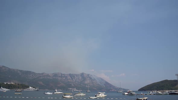 Smoke From a Fire in the Mountains Above Budva Against the Backdrop of Yachts in the Sea