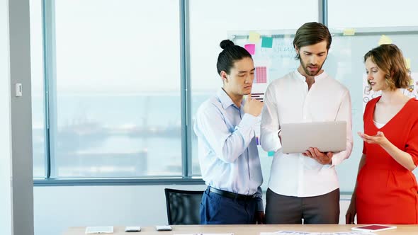 Business colleagues discussing over laptop