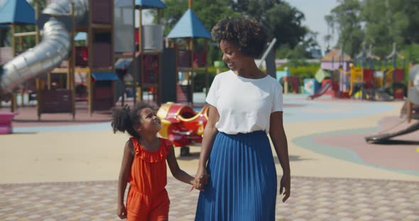 Slider Shot of Afro Mother and Daughter Holding Hands Walk at Playground