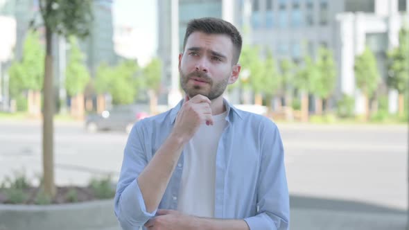 Outdoor Portrait of Pensive Young Man Thinking