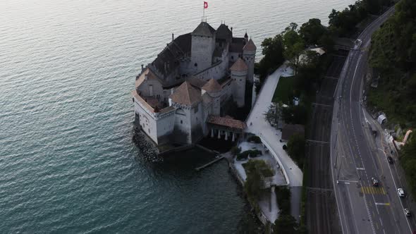 Aerial shows Chillon castle from above and tilting up to Lausanne city, Switzerland