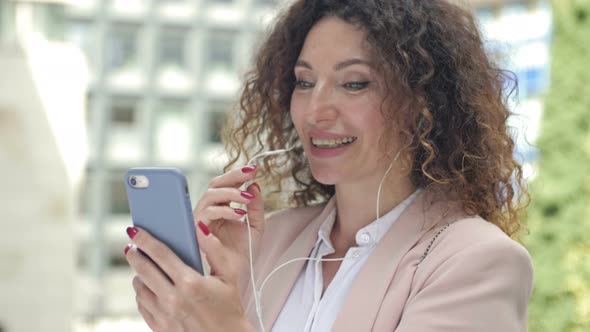 Portrait of a Business Woman Able to Work on a City Street with a Phone and Headphones