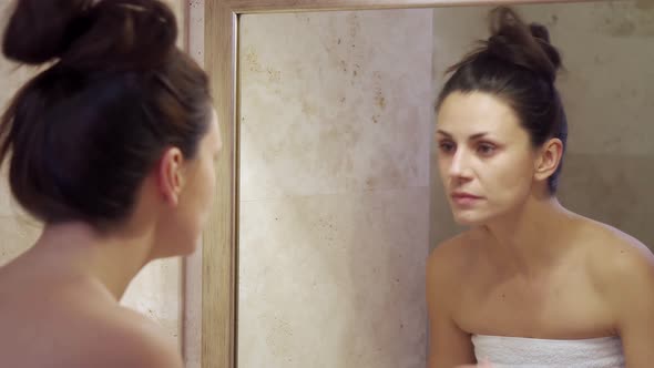 Beautiful Young Woman Doing Makeup Removal in the Mirror 