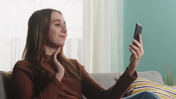 Girl Is Sitting on a Sofa and Talking on a Video Call