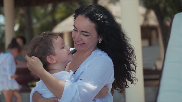 Happy Mother Hugging Her Child on the Coast. Cute Kid Kisses His Mom and Gently Hugs. Concept Mom