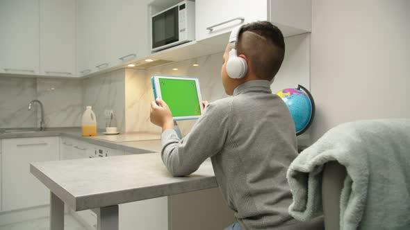 Black Boy Playing Video Game on Tablet with Chroma Key Mockup Indoors