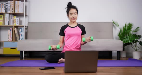 Woman looking laptop and training dumbbells