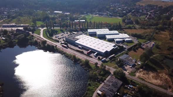 Aerial Shot Of Logistics Center With Trucks. Lake Nature.