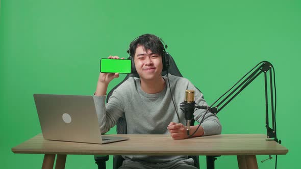 Asian Man With Headphone And Computer Showing Green Screen Mobile Phone O2 Green Screen Background