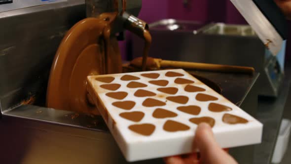 Worker filling mould with melted chocolate