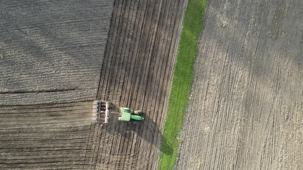 Top down view of farm being tilled for planting. Shadows cast from the tress. Straight rows in dirt.