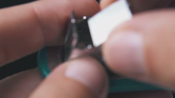 Man Opens Small Stapler to Put in Clips on Dark Background