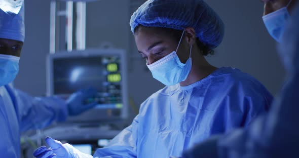 Mixed race surgeons wearing protective clothing performing surgery in operating theatre