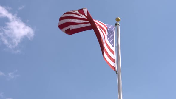 American flag waves proudly against a blue sky background. Shot in slow motion