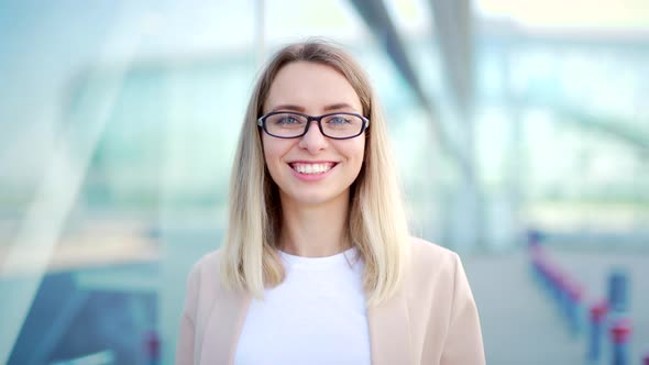 Close up portrait young blonde business woman with glasses looking at camera smiling 