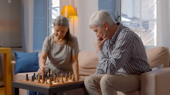 Elderly Couple Playing Chess at Home with Wife Winning Game