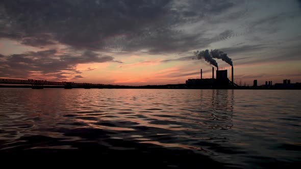 electric power station generators silhouettes at ocean coastline with radiant flaming cloud during c