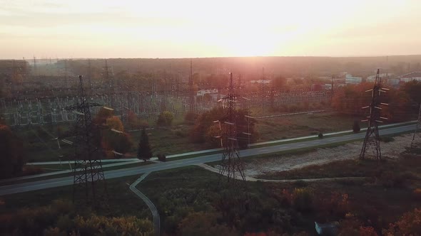 view of the structure of high-voltage lines outside the city at sunset. Camera motion back.