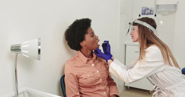 An Otolaryngologist Examines A Female Throat With A Wooden Spatula