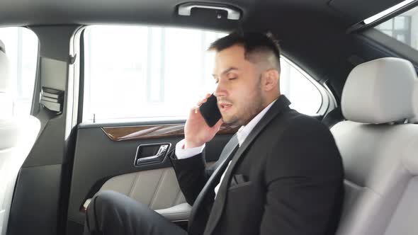 Busy Elegant Male Sitting Inside of Car and Talking on Phone