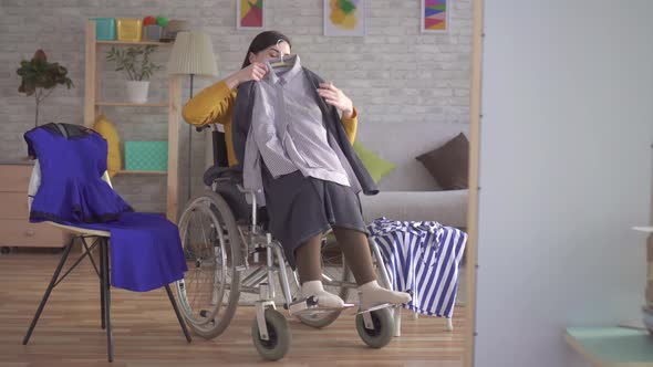 Young Disabled Girl in a Wheelchair Chooses Clothes for a Date in a Modern Apartment