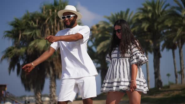 Happy Caucasian Girlfriend and African American Boyfriend Having Fun Dancing at Tourist Resort with