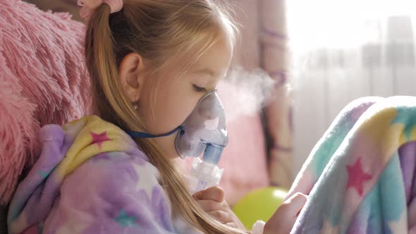 Little Girl Holds Inhaler Mask at Home. Sick Kid Breathes Through a Nebulizer. Baby Using Equipment