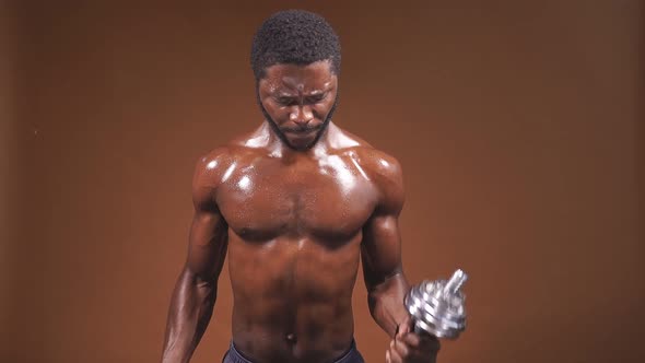 An AfricanAmerican Man Lifts Dumbbells on an Isolated Background