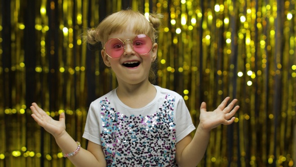 Child Dancing, Show Amazement, Fooling Around, Smiling. Girl Posing on Background with Foil Curtain