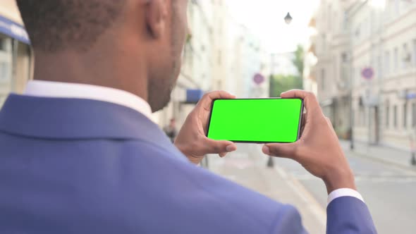 African Businessman Looking at Smartphone with Green Chroma Screen