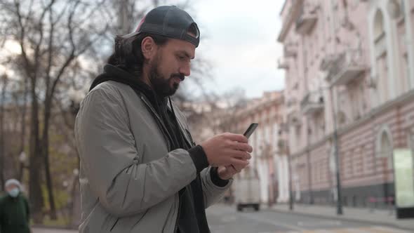 Young Handsome Man with a Phone on a City Street on a Sunny Autumn Day