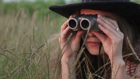 Beautiful Young Girl Looking Through Binoculars On Blue Sky Background.