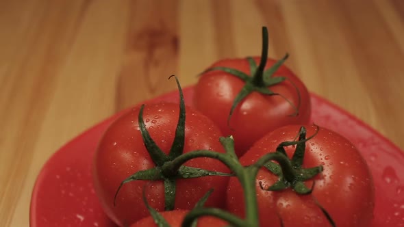 Ripe Fresh Tomatoes Branch Lies On Red Plate On The Table