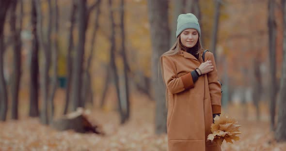 Girl Holds a Bouquet of Autumn Leaves in Her Hands in the Autumn Forest