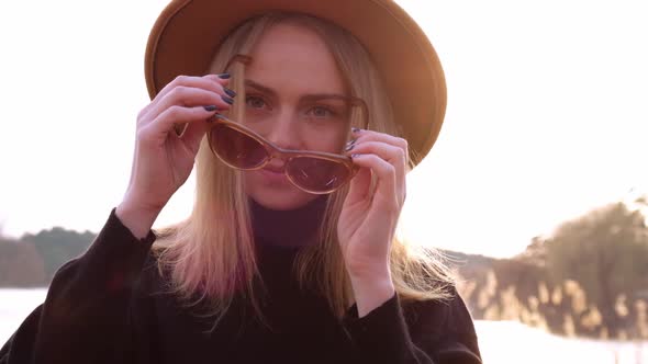 Slow motionCaucasian Blonde Woman with Beige Hat in Black Sweater Wear Sunglasses in the Countryside