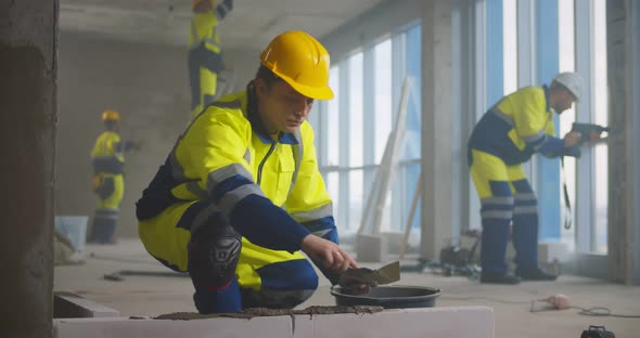 Construction Worker Using Trowel and Tools for Building Wall with Bricks and Mortar