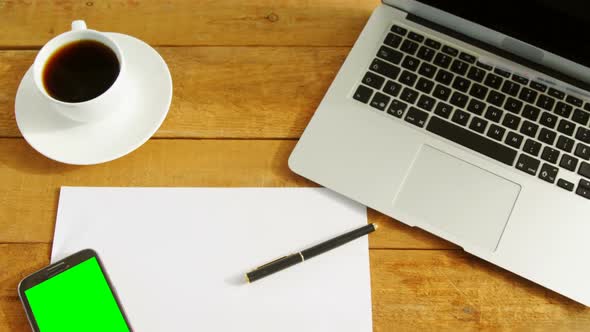 Laptop, blank paper, mobile phone, pen and coffee on table 4k