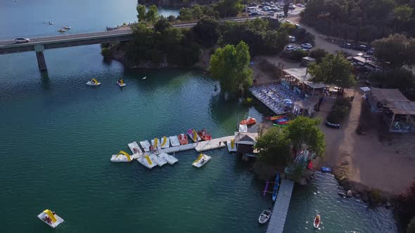 Aerial view of the jetty with boats, kayaks, green trees around and the bridge in the background