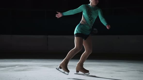 The Girl Skater Performs a Jump with the Rotation of a Triple Toe Loop in a Counter Light on an Ice