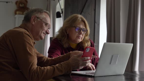 two elderly people surfing internet on laptop computer at home.