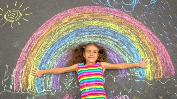 The Child Draws a Rainbow with Chalk