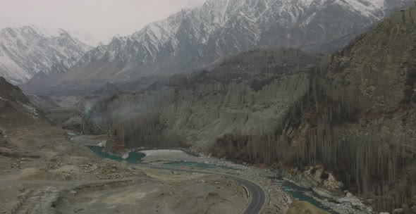 Aerial Tilt Down From Snow Capped Mountains To Hunza Valley River. Pedestal Up Dolly Forward
