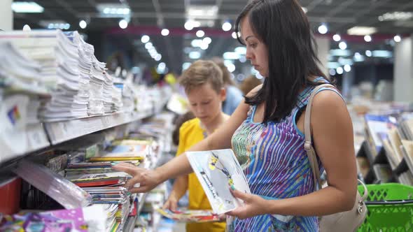 Boy choosing school supplies. Mother and son buying school supplies in store