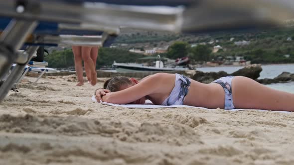 Low Angle View of a Young Girl Lying and Sunbathing on a Sandy Beach